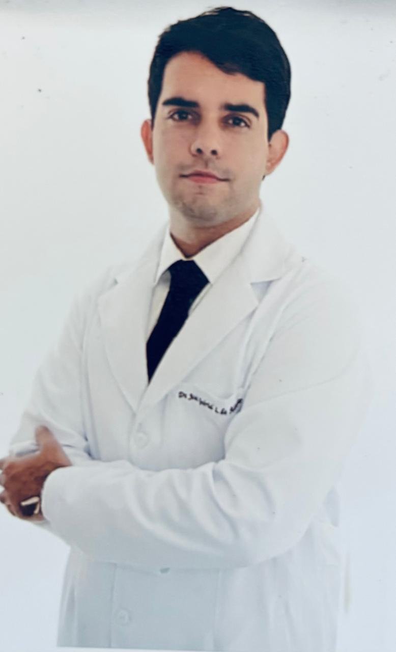 Dr. Gabriel Alencar de jaleco branco com gravata preta, braços cruzados, médico psiquiatra